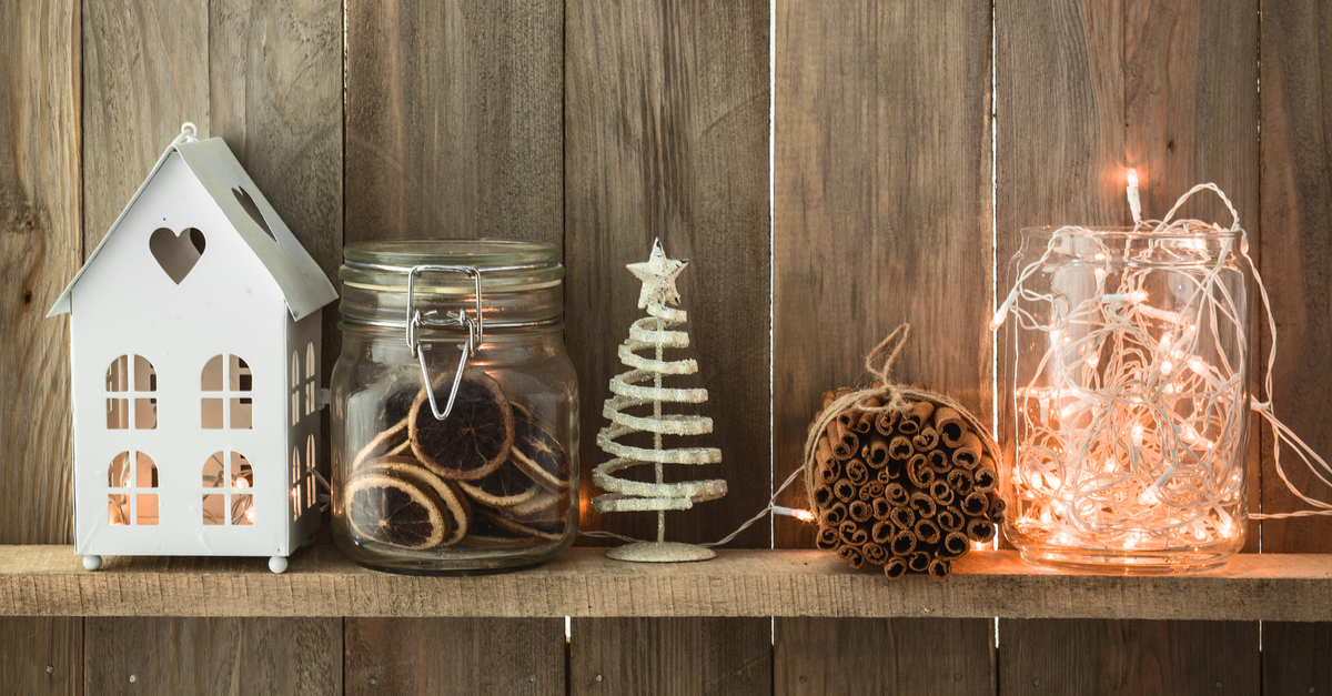 holiday decorations with tree, cookies, bundle of cinnamon sticks, lights, and a hose with a candle inside